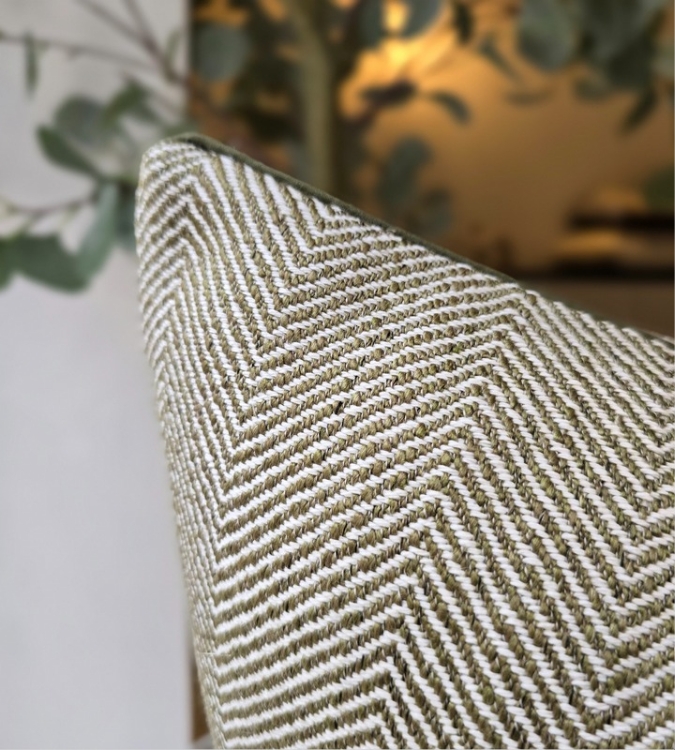 close-up view of the Nori cushion. details of the herringbone pattern and green piping on the edge can be seen