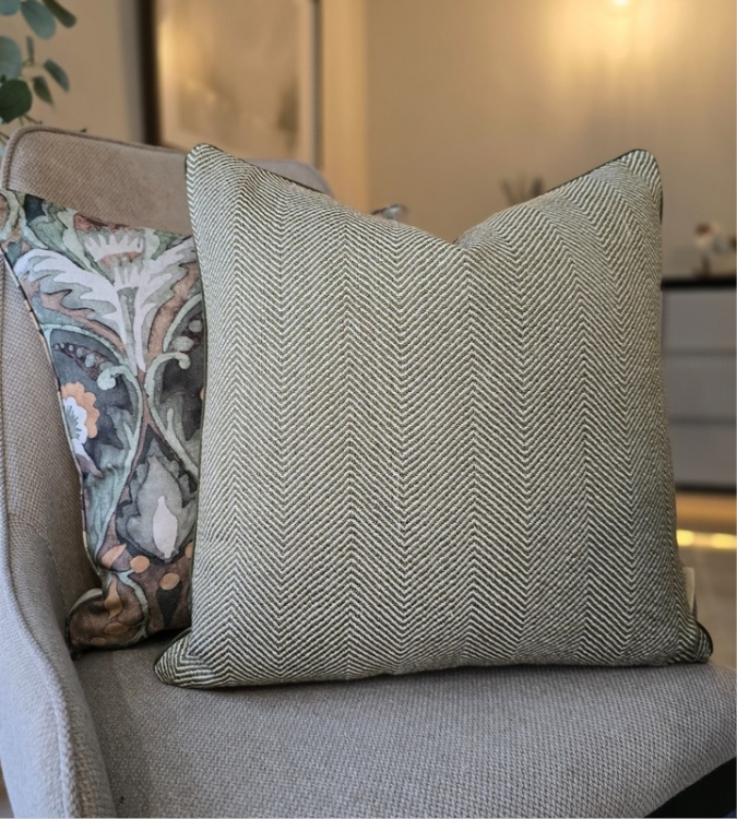A green herringbone square cushion paired with a complimentary ornate patterned cushion in the designer fabric by prestigious textiles