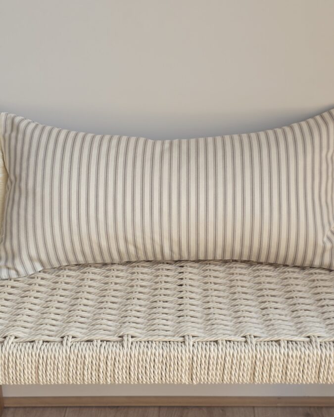 Ticking stripe bolster cushion in mushroom with a herringbone weave, finished with warm- white cotton fringe and a European duck feather inner.